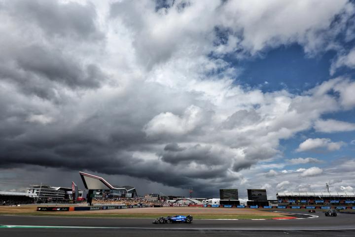 Carlos Sainz driving the Atlassian Williams Racing FW47 at Silverstone with the sky half-filled with grey clouds