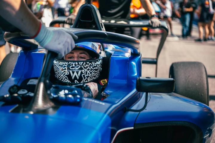 Lia Block sits in her Williams F1 Academy Car with her helmet on